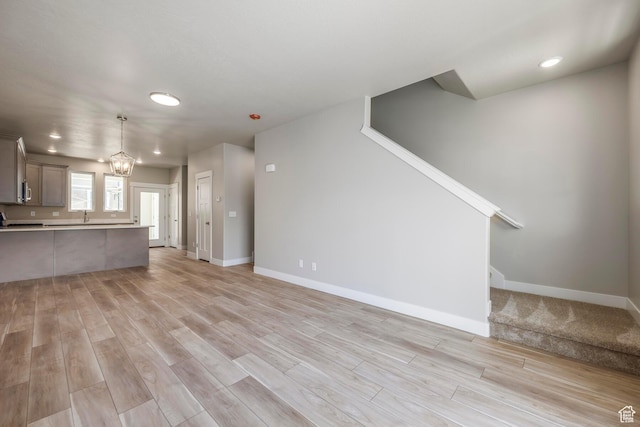 unfurnished living room with a notable chandelier and light wood-type flooring