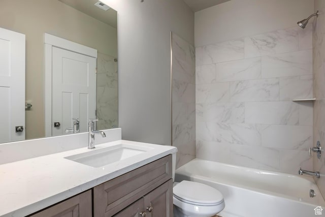 full bathroom featuring tiled shower / bath, vanity, and toilet