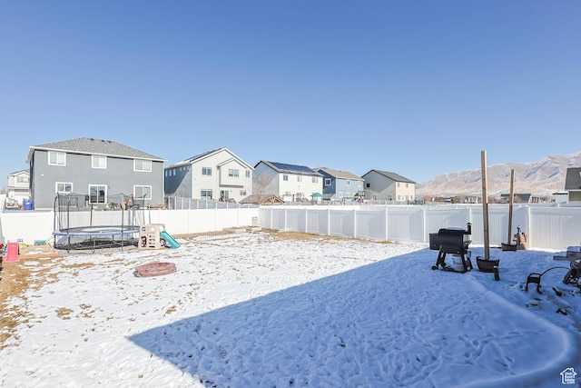 snowy yard featuring a trampoline and a mountain view