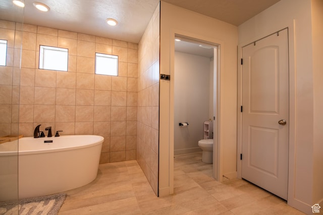 324 S Hayes Well Ln, Saratoga Springs, UT 84045 - bathroom with tile walls, toilet, and a freestanding bath