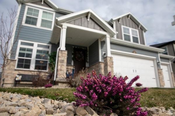 craftsman-style home with stone siding, board and batten siding, and a garage