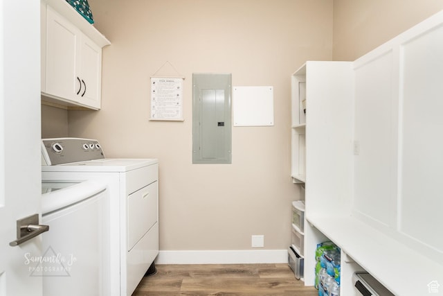 clothes washing area featuring cabinets, washing machine and clothes dryer, electric panel, and light hardwood / wood-style flooring