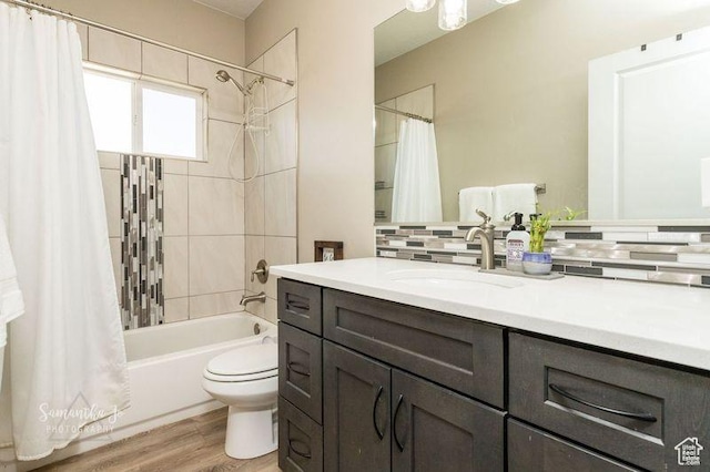full bathroom with hardwood / wood-style floors, backsplash, vanity, shower / tub combo, and toilet