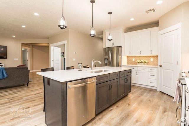 kitchen with pendant lighting, an island with sink, white cabinets, and appliances with stainless steel finishes