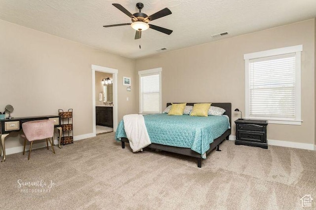 bedroom with ensuite bath, light carpet, and a textured ceiling