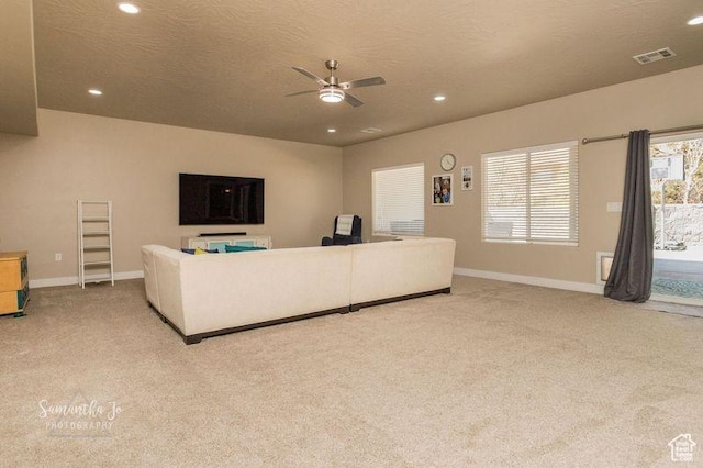 living room featuring ceiling fan, light carpet, and a textured ceiling
