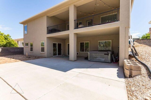 rear view of property featuring a balcony, a hot tub, and a patio