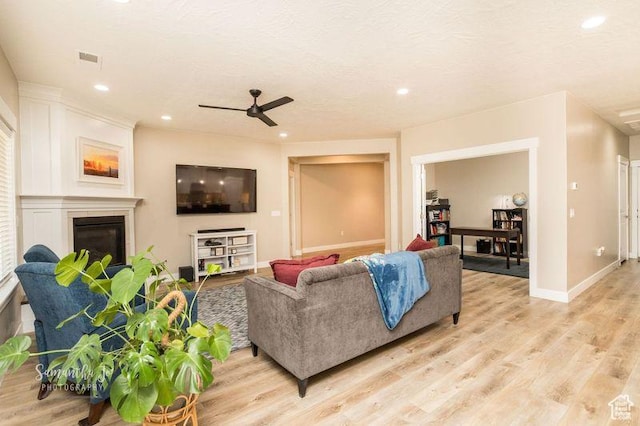 living room featuring a textured ceiling, light hardwood / wood-style floors, and ceiling fan