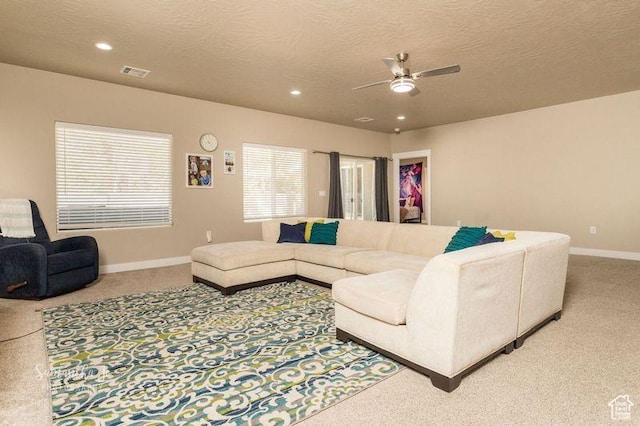 carpeted living room with ceiling fan and a textured ceiling