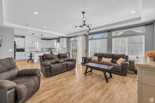 2144 S 120 E, Heber City, UT 84032 - living room with a raised ceiling, a textured ceiling, light wood-style flooring, a chandelier, and recessed lighting