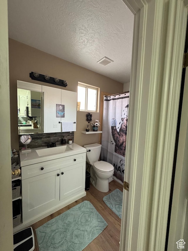 1150 W Red Hills Pkwy Unit 123, Washington, UT 84780 - bathroom featuring a shower with shower curtain, vanity, wood-type flooring, a textured ceiling, and toilet
