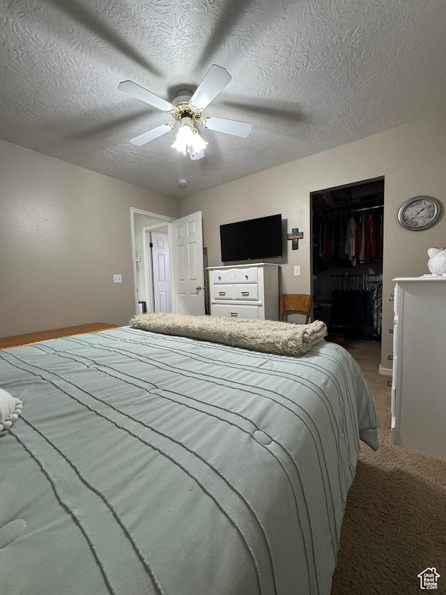1150 W Red Hills Pkwy Unit 123, Washington, UT 84780 - bedroom featuring a walk in closet, a textured ceiling, a closet, ceiling fan, and carpet