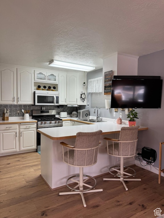 1150 W Red Hills Pkwy Unit 123, Washington, UT 84780 - kitchen featuring stainless steel appliances, white cabinetry, a kitchen bar, and kitchen peninsula