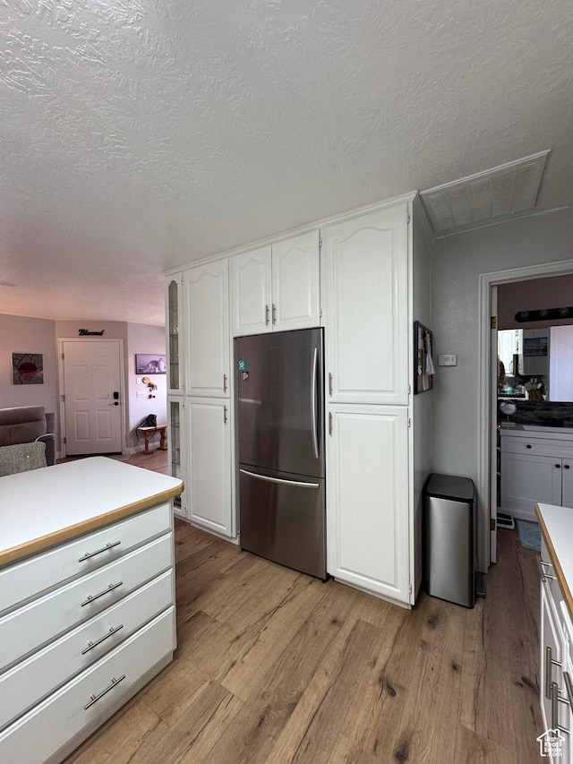 1150 W Red Hills Pkwy Unit 123, Washington, UT 84780 - kitchen featuring white cabinetry, stainless steel fridge, light hardwood / wood-style flooring, and a textured ceiling