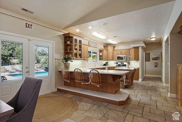 kitchen with french doors, a kitchen bar, vaulted ceiling, appliances with stainless steel finishes, and kitchen peninsula