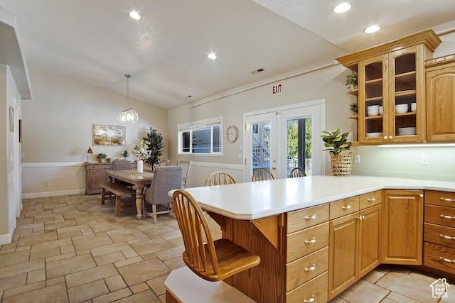 kitchen with vaulted ceiling, a kitchen bar, hanging light fixtures, kitchen peninsula, and french doors