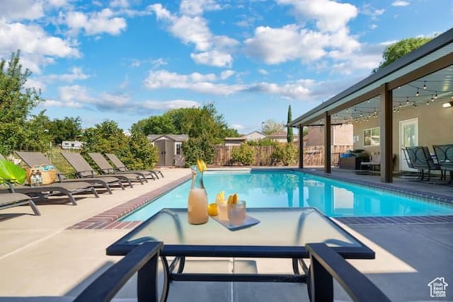 view of swimming pool featuring a shed and a patio area