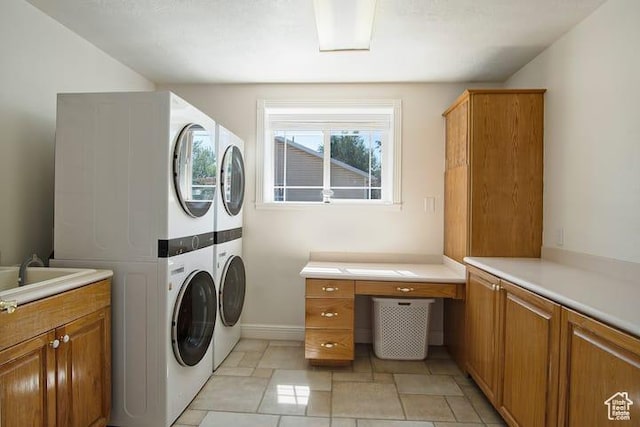 washroom with stacked washer and dryer, sink, and cabinets