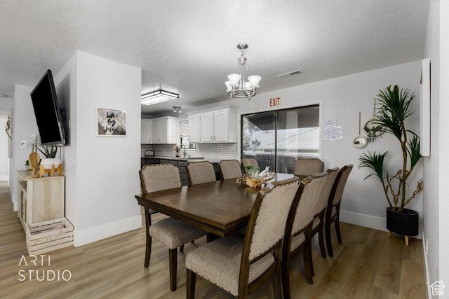 dining space featuring a wealth of natural light, a chandelier, a textured ceiling, and light wood-type flooring