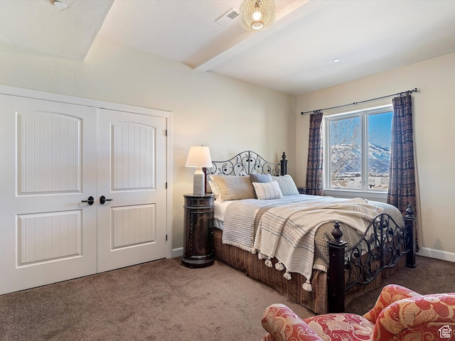bedroom featuring a closet, carpet flooring, and beam ceiling