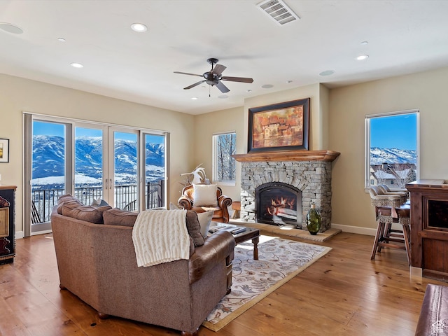 living room featuring ceiling fan, a mountain view, hardwood / wood-style floors, and a fireplace