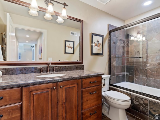 full bathroom featuring enclosed tub / shower combo, vanity, and toilet