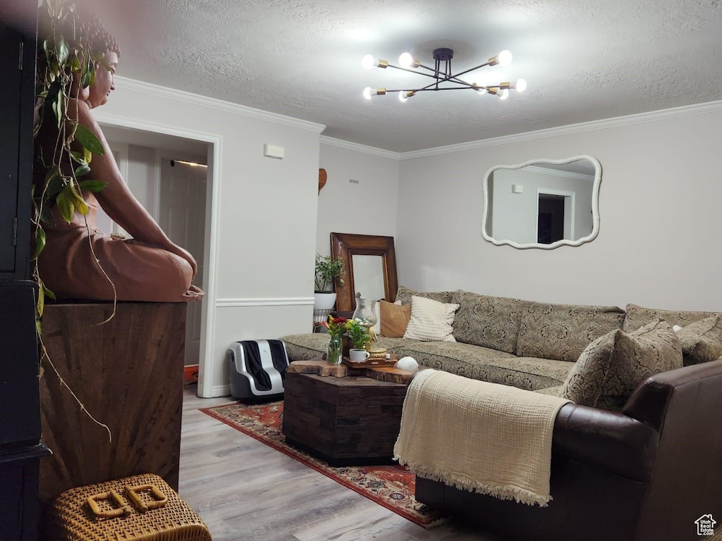 living room with crown molding, a chandelier, a textured ceiling, and light wood-type flooring