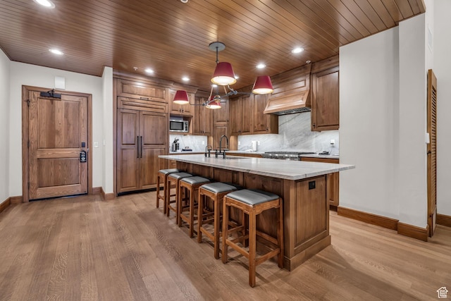 7700 Stein Way Unit 215, Park City, UT 84060 - kitchen with custom exhaust hood, paneled refrigerator, pendant lighting, light stone countertops, and a kitchen island with sink