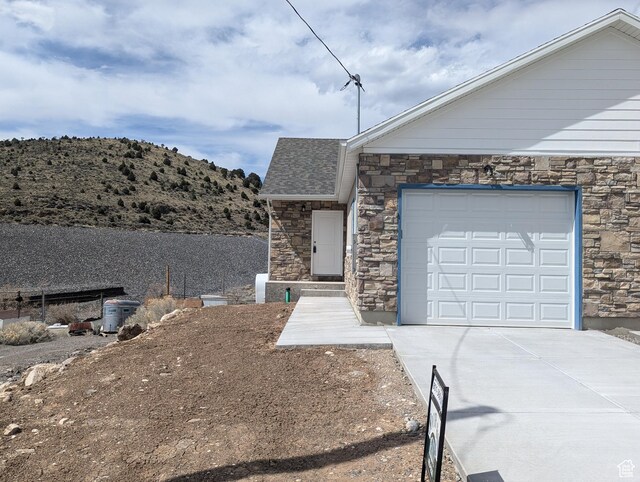 350 W Dublin S, Eureka, UT 84628 - view of front of house featuring a shingled roof, stone siding, an attached garage, a mountain view, and driveway
