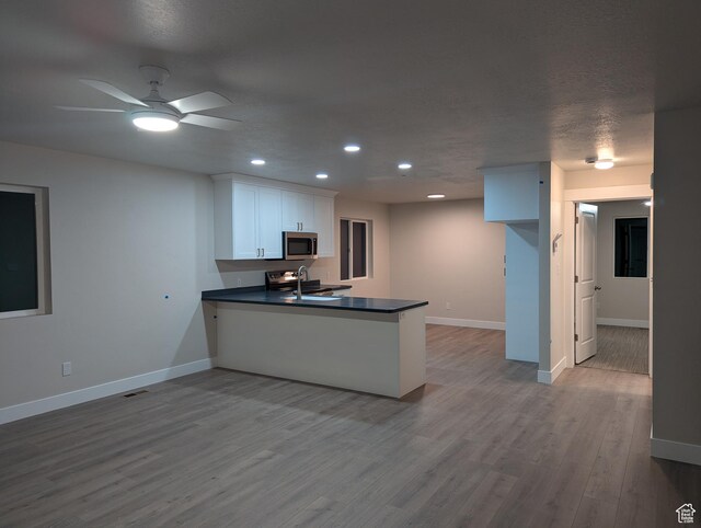 350 W Dublin S, Eureka, UT 84628 - kitchen featuring stainless steel microwave, baseboards, a peninsula, dark countertops, and a sink