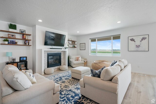 598 S Otto Ln, Grantsville, UT 84029 - living area featuring a glass covered fireplace, baseboards, recessed lighting, a textured ceiling, and wood finished floors