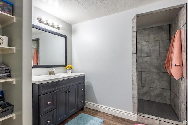 518 N 1980 E, Spanish Fork, UT 84660 - bathroom featuring wood finished floors, tiled shower, a textured ceiling, baseboards, and vanity