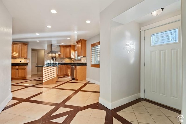 kitchen featuring light tile patterned flooring, sink, wall chimney range hood, and backsplash