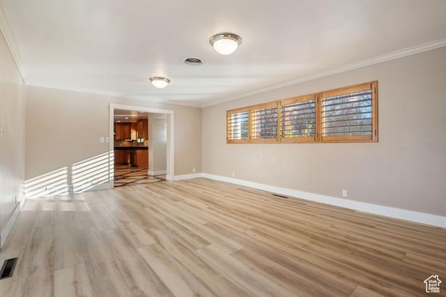 empty room featuring ornamental molding and light wood-type flooring