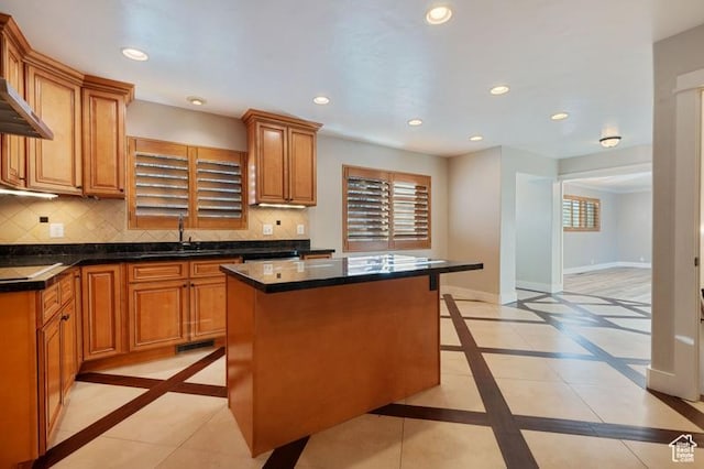 kitchen with black electric cooktop, a center island, sink, and backsplash