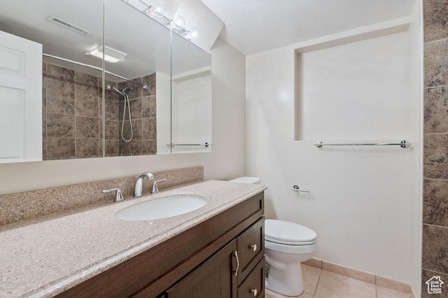 bathroom with tiled shower, tile patterned floors, toilet, and vanity