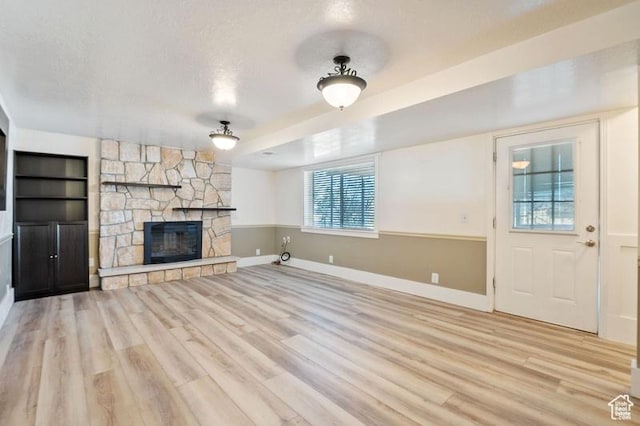 unfurnished living room featuring a fireplace, light hardwood / wood-style floors, and a textured ceiling