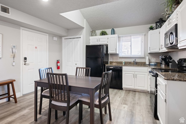 dining room featuring sink, a textured ceiling, and light hardwood / wood-style floors