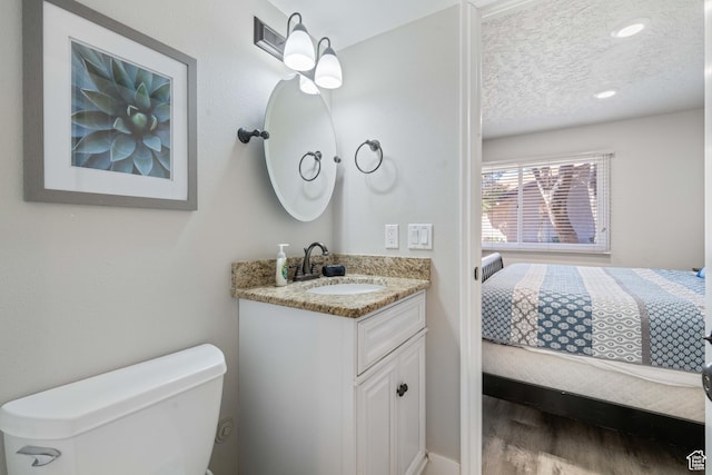 bathroom featuring wood-type flooring, toilet, a textured ceiling, and vanity