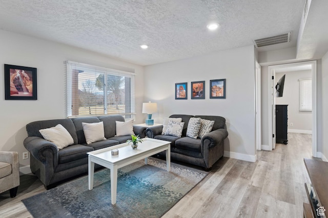 living room with a textured ceiling and light hardwood / wood-style floors