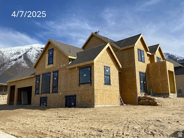 view of side of home featuring roof with shingles and a mountain view