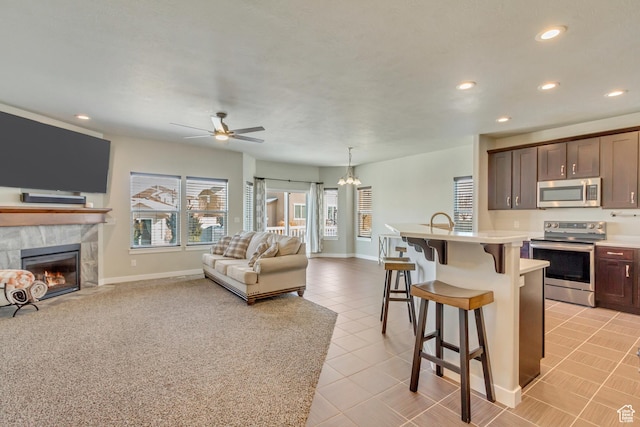 kitchen featuring stainless steel appliances, light countertops, open floor plan, a kitchen bar, and recessed lighting