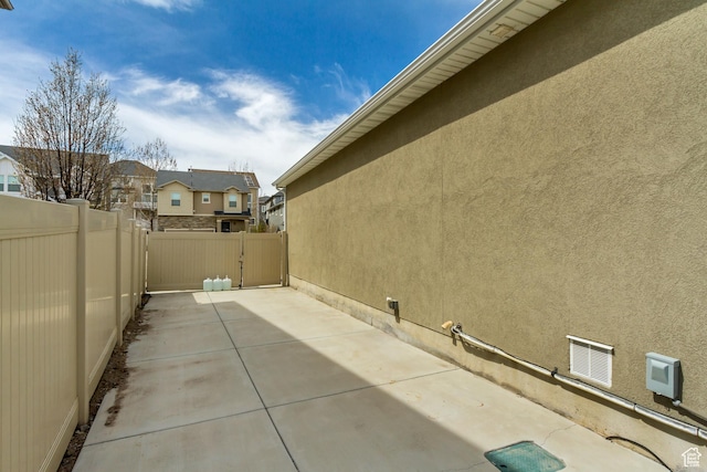 view of side of home featuring stucco siding, a patio area, and fence