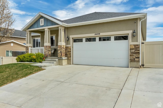 craftsman inspired home with concrete driveway, stone siding, an attached garage, and covered porch