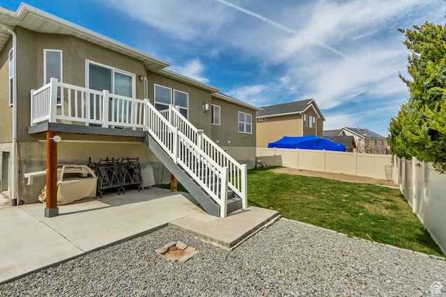 back of property featuring a patio, a wooden deck, a fenced backyard, a lawn, and stucco siding
