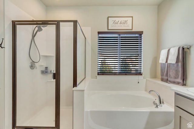 bathroom with a stall shower, a bath, and vanity