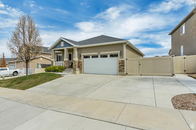 view of front of property with a garage, a gate, stone siding, concrete driveway, and fence