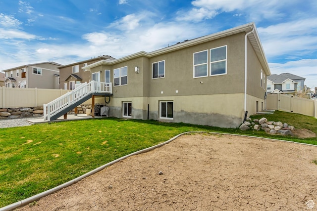 back of property with stucco siding, stairway, fence, a residential view, and a lawn