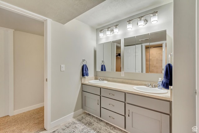 bathroom featuring baseboards, double vanity, and a sink