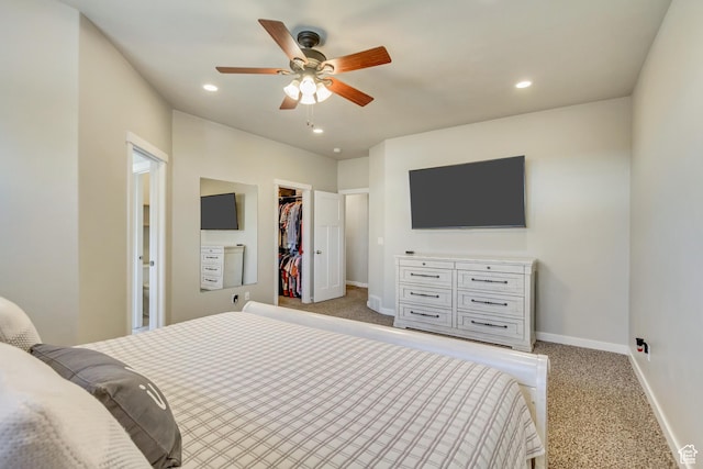 bedroom featuring a walk in closet, light colored carpet, and baseboards